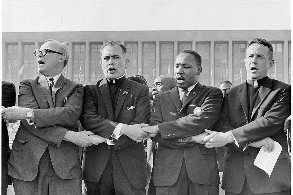 The Rev. Theodore Hesburgh, center left, holds hands with the Rev. Martin Luther King Jr. while singing “We Shall Overcome” during a civil rights rally at Soldier Field in Chicago on June 21, 1964. Photo courtesy of OCP Media